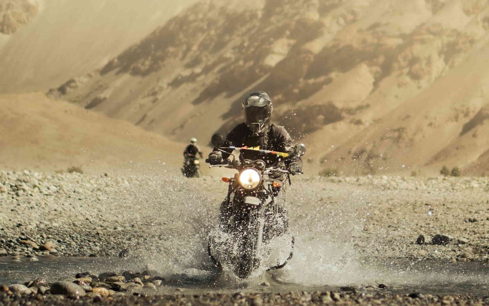 Motorcyclist riding through a river crossing on an off-road Ladakh tour in the Himalayas