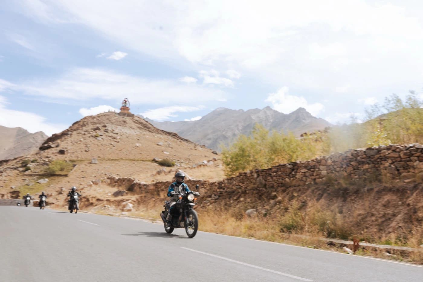 Motorcyclists riding past a hilltop stupa in the Lungnak valley