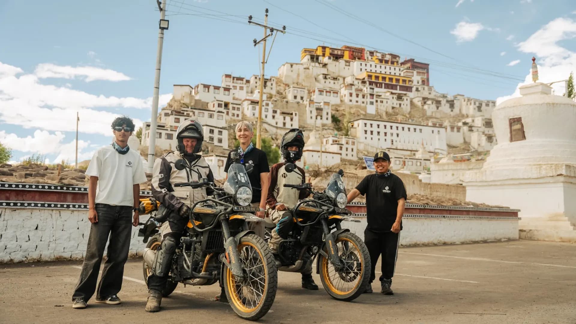 Riders with two Royal Enfield Himalayan 450 motorcycles stopped on the road below Thiksey Monastery near Leh, Ladakh