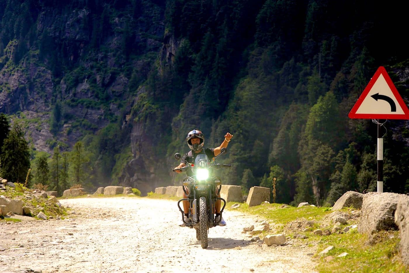 Rider waving from a Royal Enfield Himalayan 450 at the top of the Hamta road near Sethan