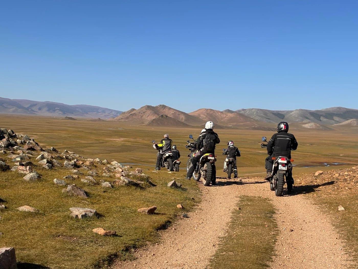 Riders on a dirt track across the Mongolian steppe on a Mongolia motorcycle tour