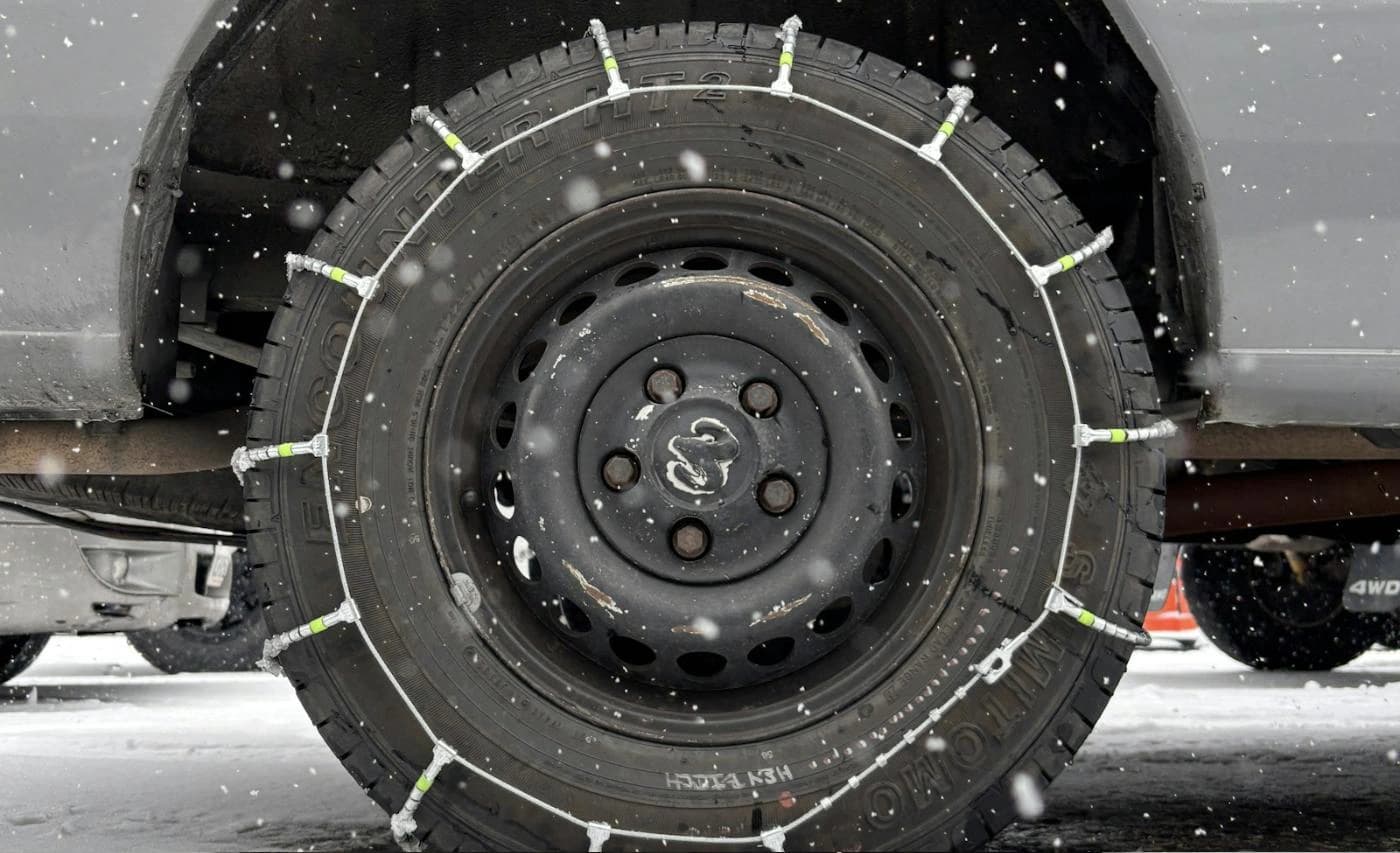 Snow chains fitted on a car tyre for driving on winter roads