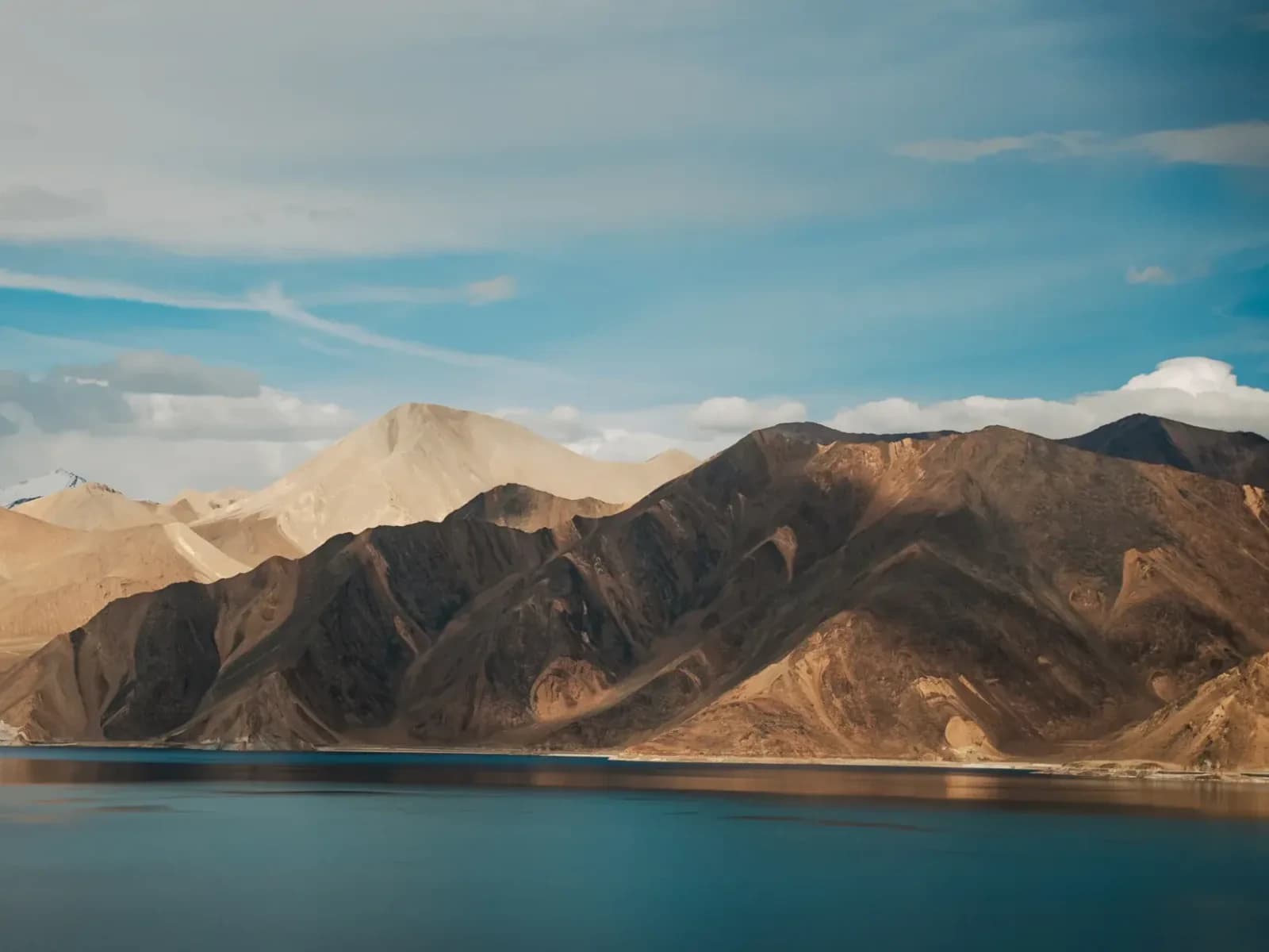 Turquoise water of Pangong Tso below barren brown mountains in Ladakh