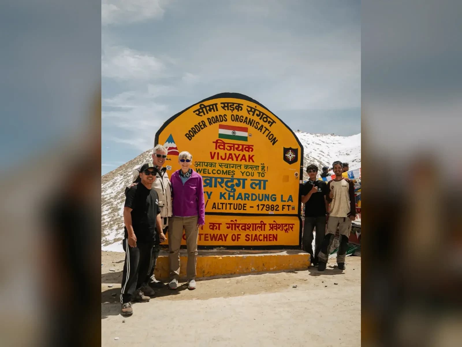 Motorcycle tour group posing at the Khardung La sign in Ladakh