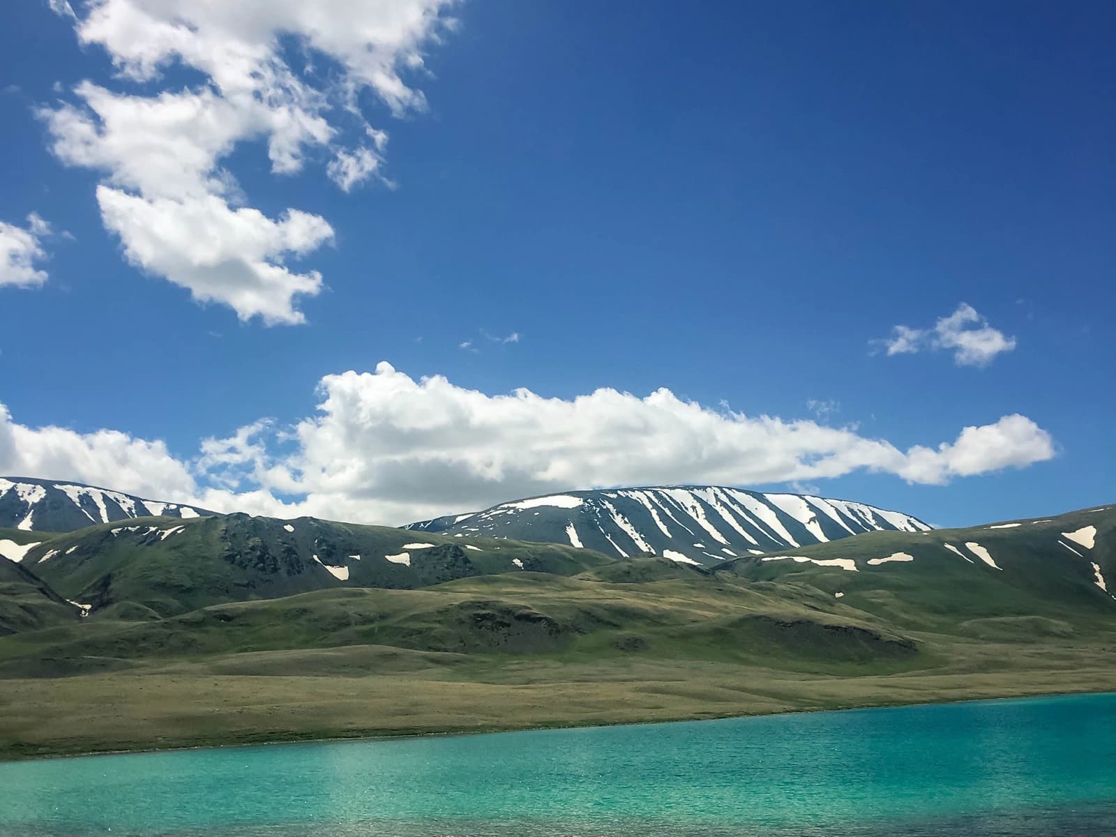 Turquoise lake below snow-covered mountains in Mongolia