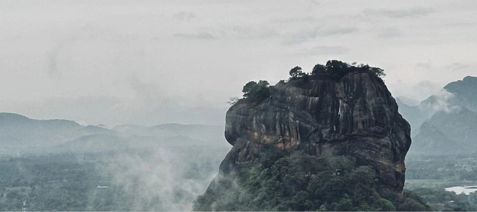 Sigiriya Rock Fortress rising through morning mist in Sri Lanka's hill country