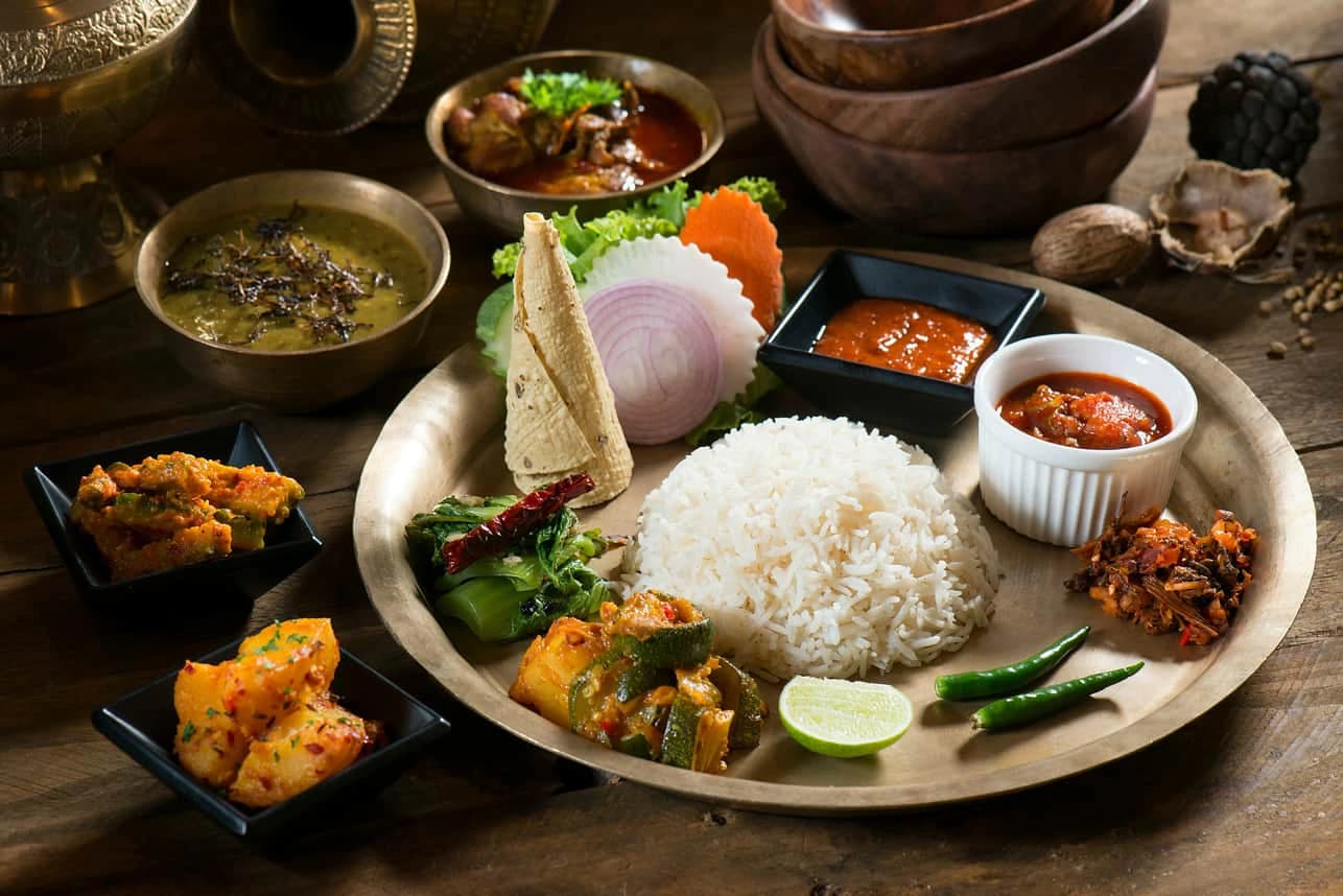 Traditional Nepali thali served with rice, lentil soup, vegetable curries, pickles, greens, and chutneys.