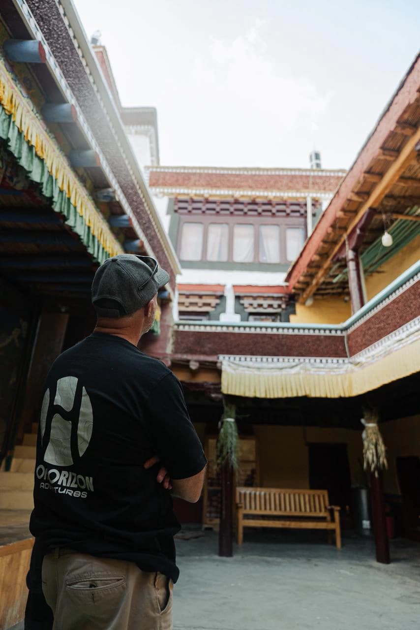 A traveller exploring the traditional courtyard and Tibetan Buddhist architecture of Lamayuru Monastery in Ladakh. Lamayuru is one of the most distinctive cultural stops on a Himalayan motorcycle tour through the region.