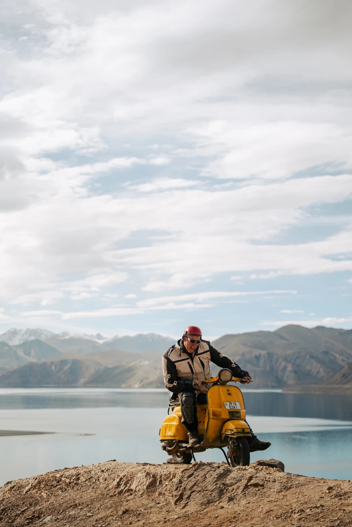 A traveller enjoying the spectacular landscape of Pangong Lake in Ladakh, with the deep blue lake and rugged Himalayan mountains creating an unforgettable backdrop.