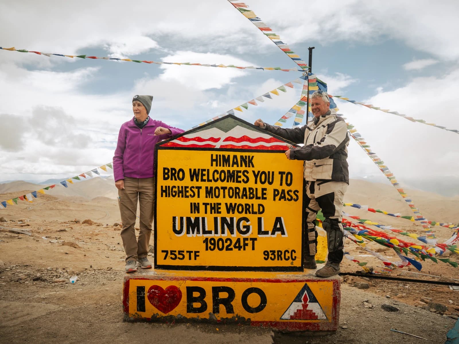 Two travelers posing at the Umling La Pass sign in Ladakh