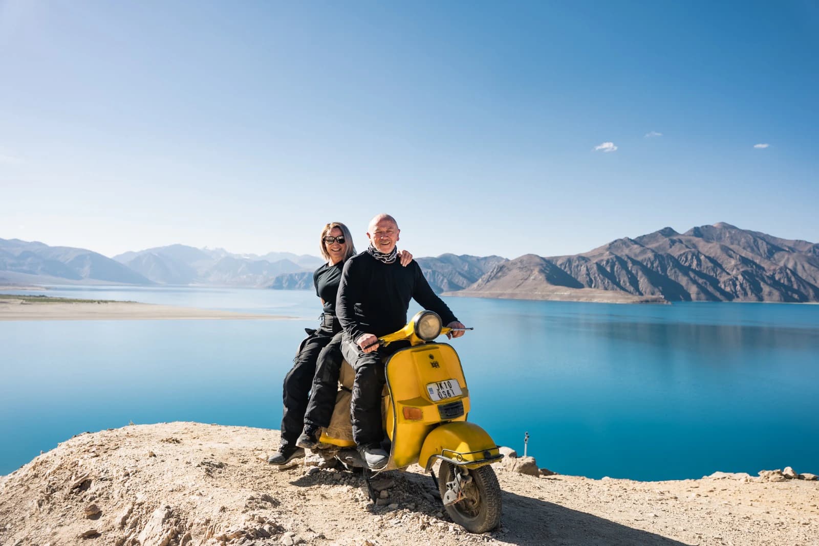Couple on a yellow scooter beside Pangong Lake in Ladakh