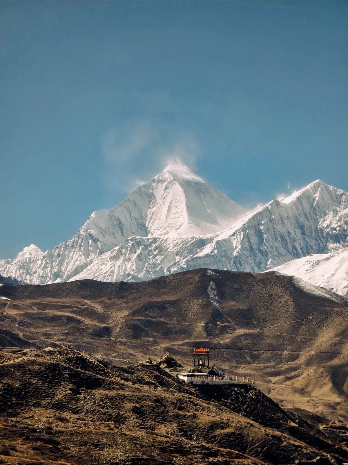Snow-covered Himalayan mountains rising above a rugged high-altitude landscape
