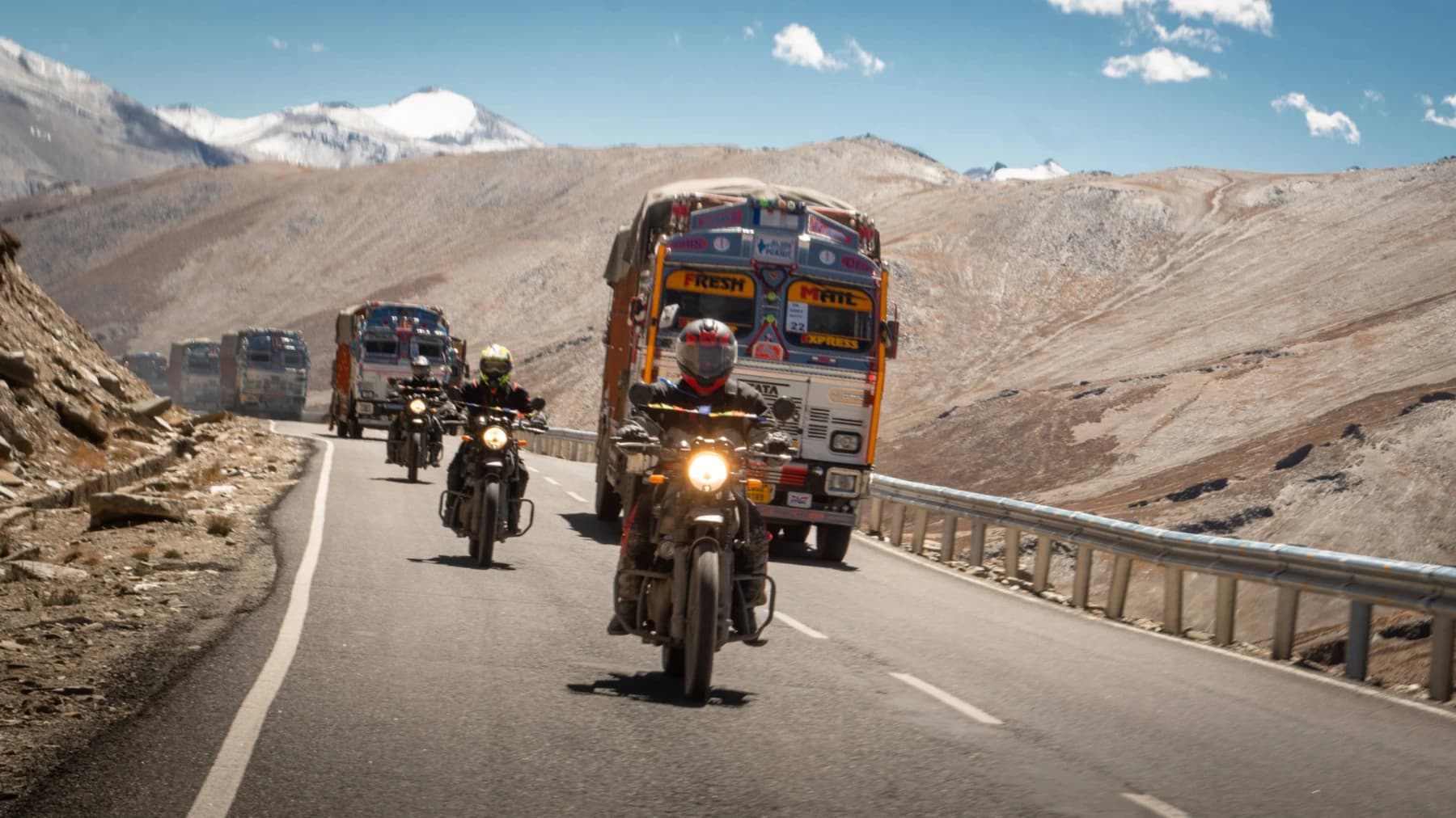 Motorcyclists riding across a vast Himalayan mountain road