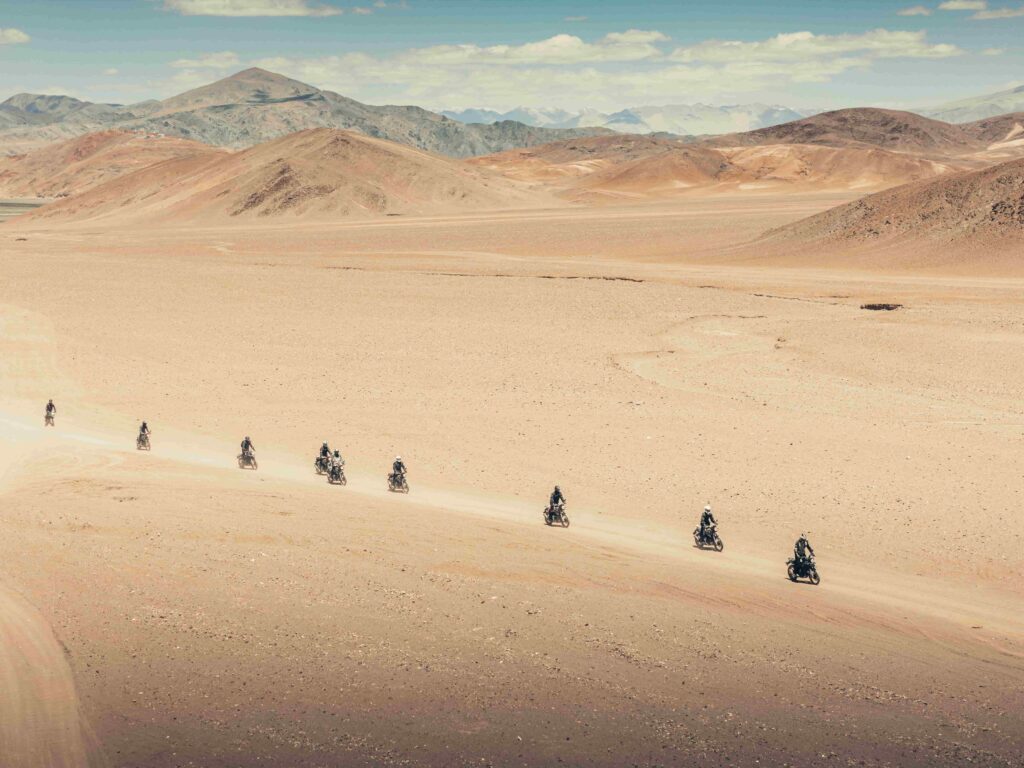 Motorcyclists riding across a vast desert landscape in Ladakh on the route from Hanle to Umling La, the world’s highest motorable road
