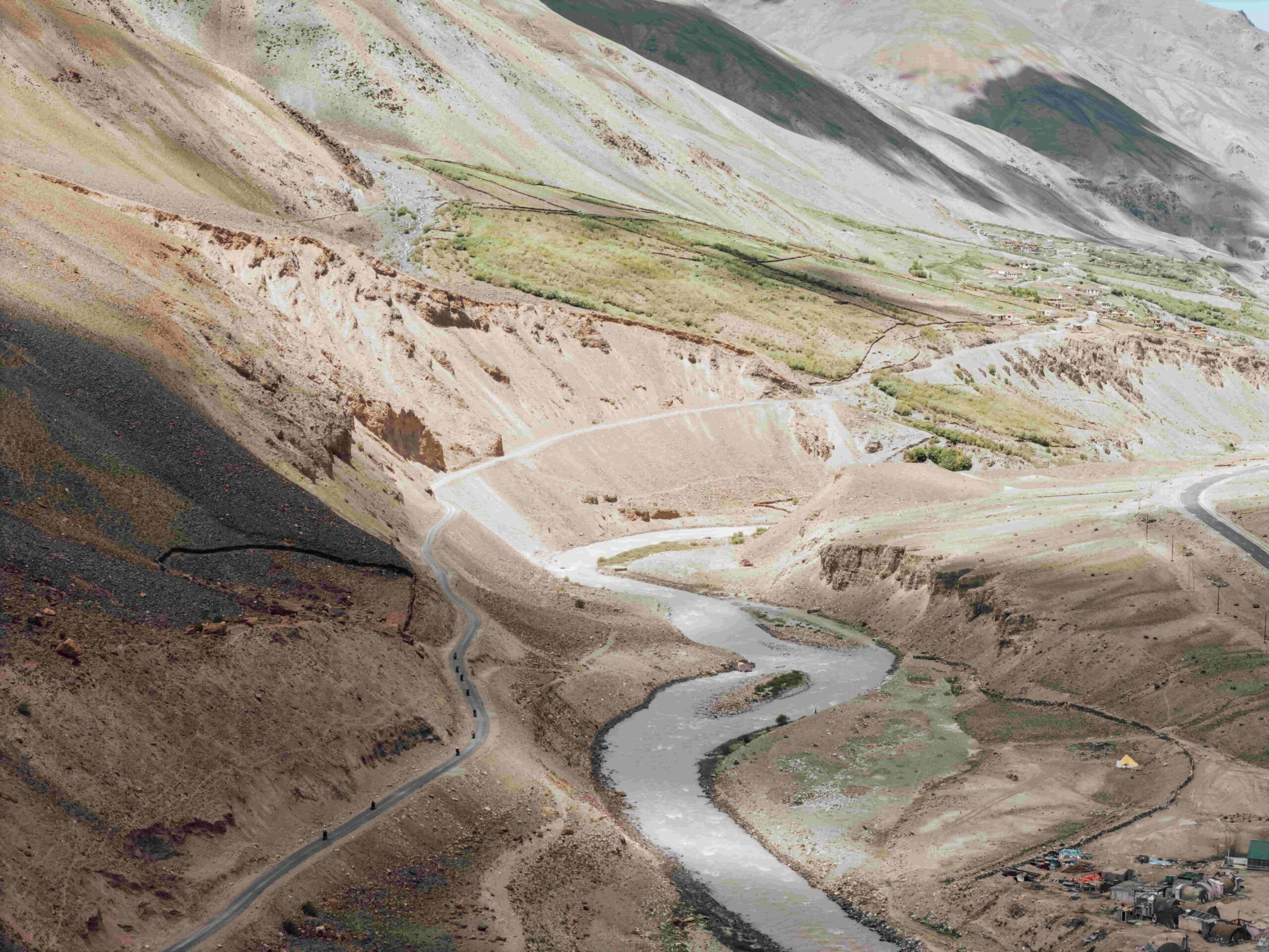 Aerial view of a winding road and river flowing through a rugged valley in the Indian Himalayas surrounded by barren mountains